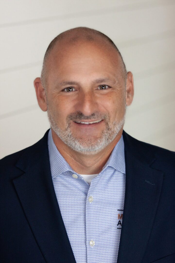 A man with a shaved head and beard wearing a suit.